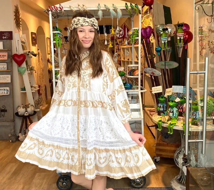 Ein Model prästeniert ein helles Sommerkleid im Hintergrund sieht man Dekoartikel im Geschäft von Viva la Vida in Prien.
