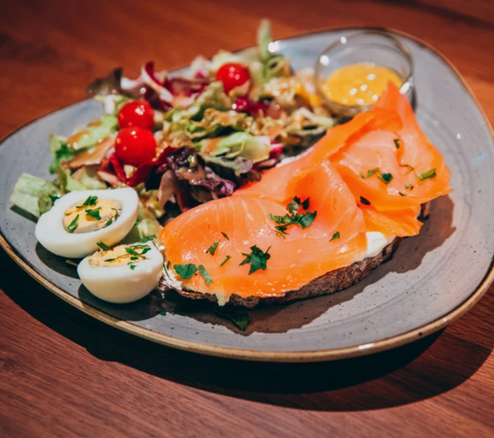 Ein Teller mit Speisen (Salat, Ei, Brot und Lachs) serviert wird dies im Scherzl Prien.