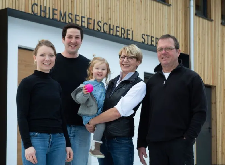 die Familie Stephan der Chiemseefischerei vor dem neugebauten Gebäude in Holzständer