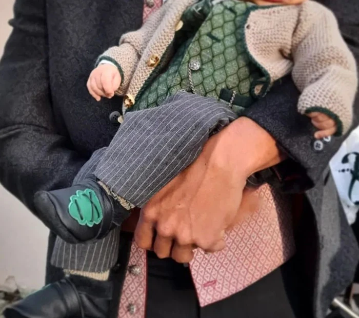Ein Kleinkind in Kindertracht auf den Arm vor dem Geschäft Bartl Prien am Chiemsee