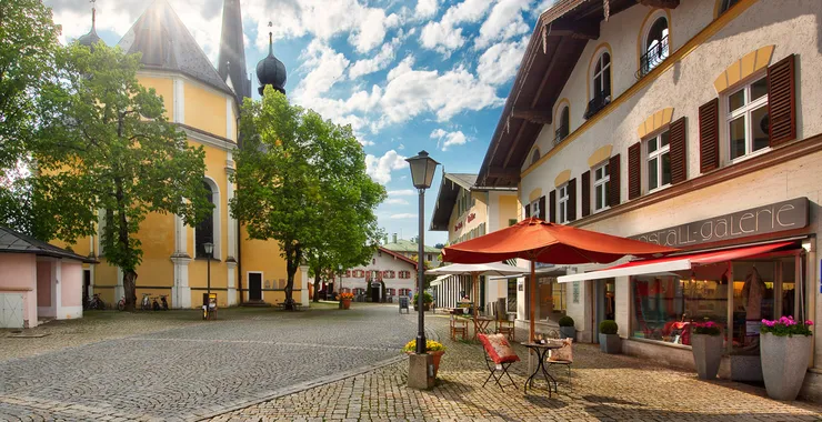 Geschäftstraße in Prien, auf der linken Seite ist die Kirche und auf der rechten Seite sind Geschäfte.