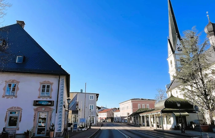 Blick in die Rathausstraße von Prien. Auf der rechten Seite ist das Geschäft Seeoptik Prien zu sehen und auf der linken Seite die Kirche.