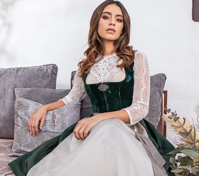 Das Modell trägt ein edles Samtdirndl mit Spitzenbluse von Marjo aus der Chiceria Prien.