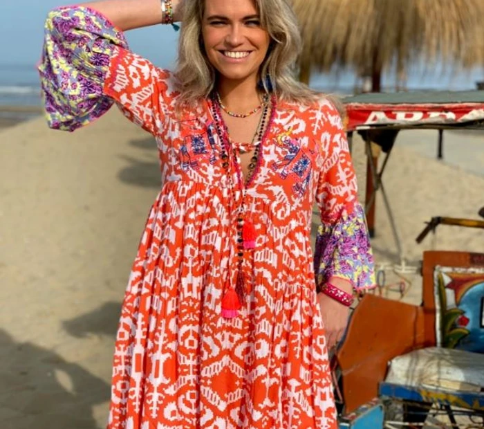 Model präsentiert ein organges Sommerkleid von Kunstwerksatt Prien am Strand