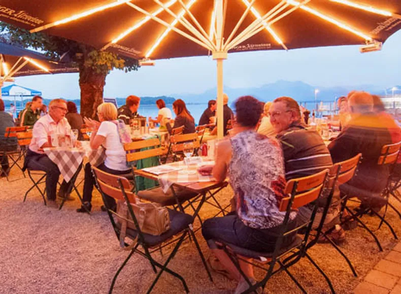 Biergarten mit Seeblick im Westernacher Prien am Chiemsee Abendstimmung unter Bäumen