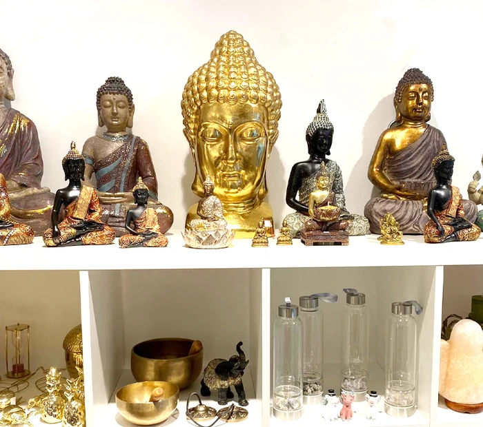 In einem Regal stehen Buddah-Figuren, Klangschalen, Salzstein dekoriert im Geschäft bei Viva la Vida in Prien