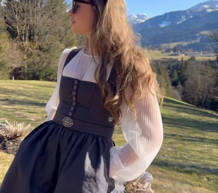Präsentiert wird ein anthrazitfarbenes Dirndl mit weißer Bluse, erhältlich in der Chiceria Prien, solange Vorrat reicht
