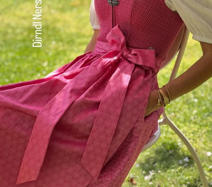 Präsentiert wird ein Dirndl in beere mit weißer Bluse, erhältlich in der Chiceria Prien, solange Vorrat reicht