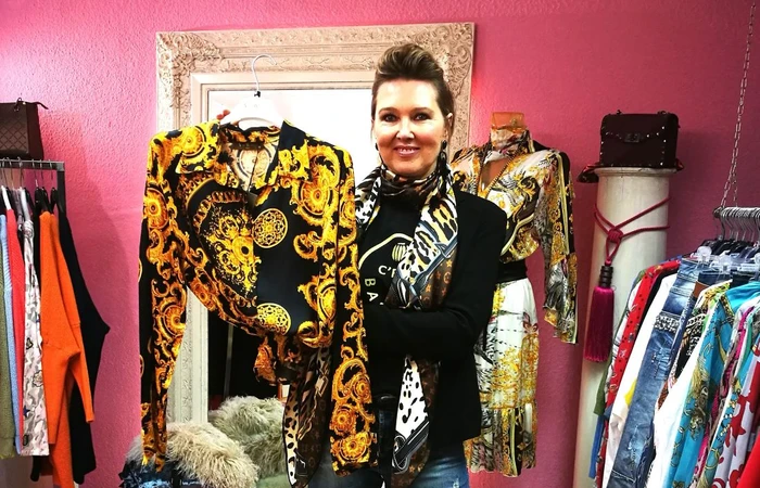 Inhaberin Polzin zeigt Bluse im Versacestil schwarz mit goldenen Ornamenten