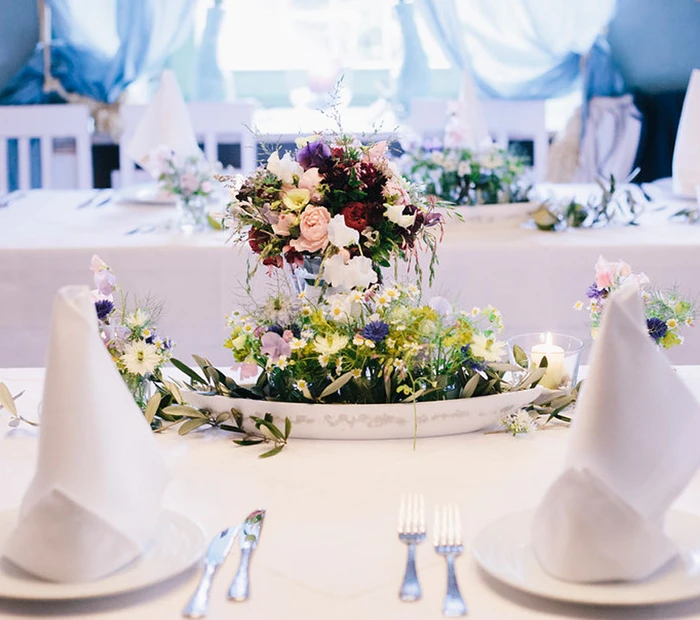 Ein gedeckter Hochzeitstisch mit einem Blumenarrangement von Blumenhandwerk Prien