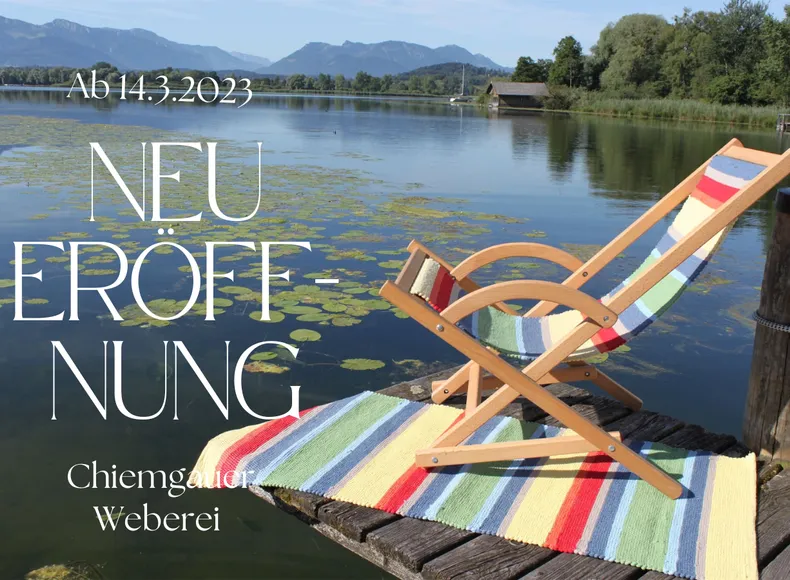 Am See auf einen Steg sind ein Liegestuhl und ein Teppich der Chiemgauer Weberei ausgestellt.