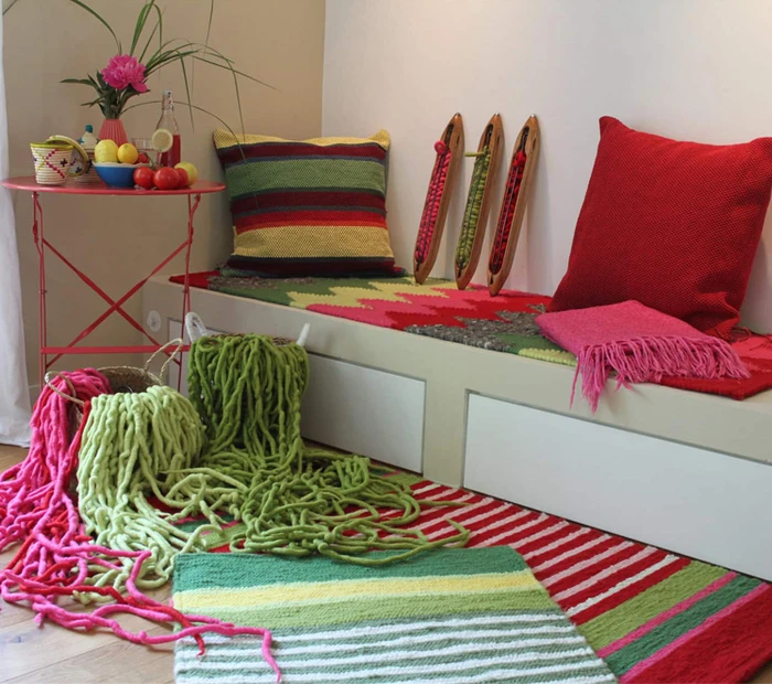 In einem Zimmer sind Teppiche, Kissen, Wolle, Decken aus der Chiemgau Weberei ausgestellt.